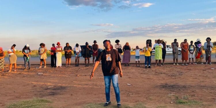 Lwazi Mnisi, a resident of Lawley, leads the prayer at R558 and Walter Road intersection (Image: Viki Stuurman)